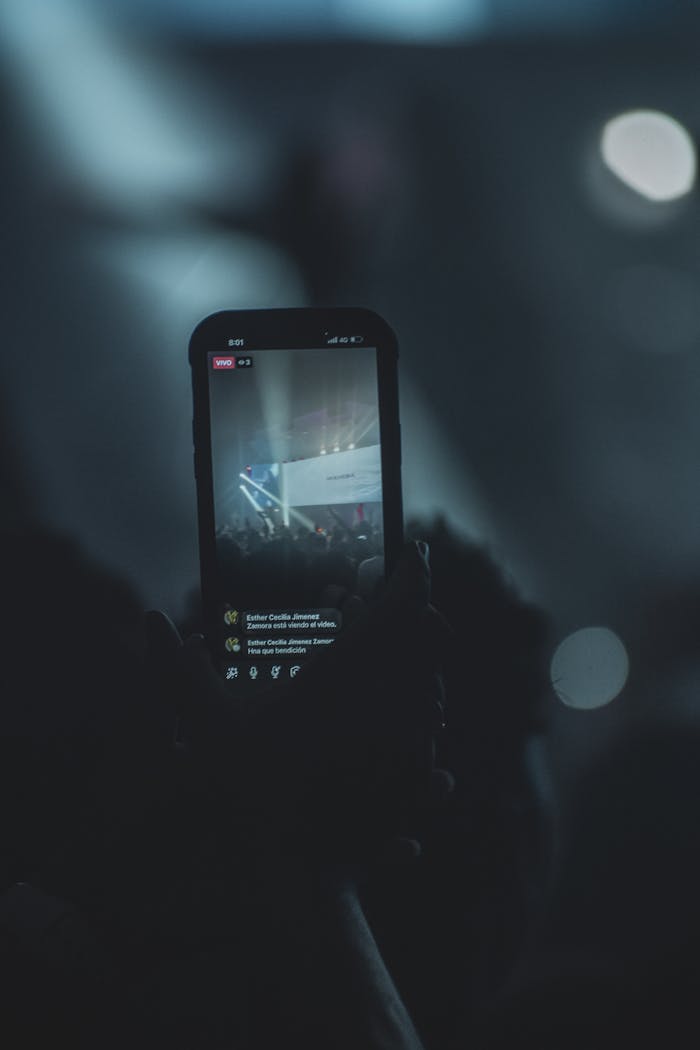 Focused image of a smartphone capturing a live concert scene with blurred audience.