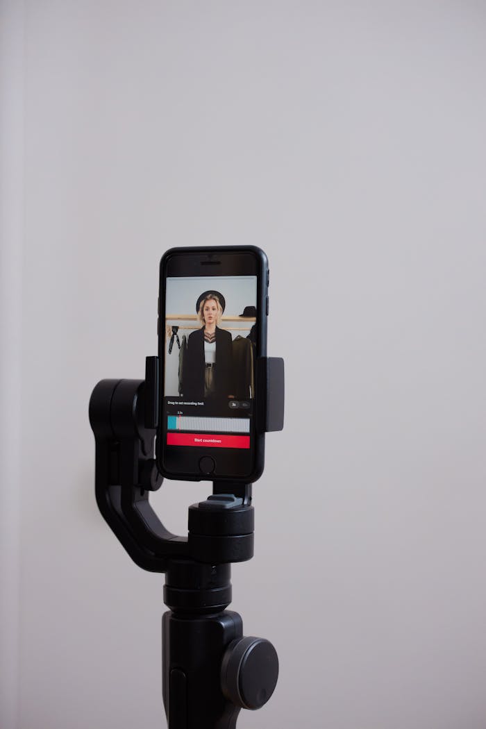 Smartphone on a tripod with a person in the screen, live streaming indoors.